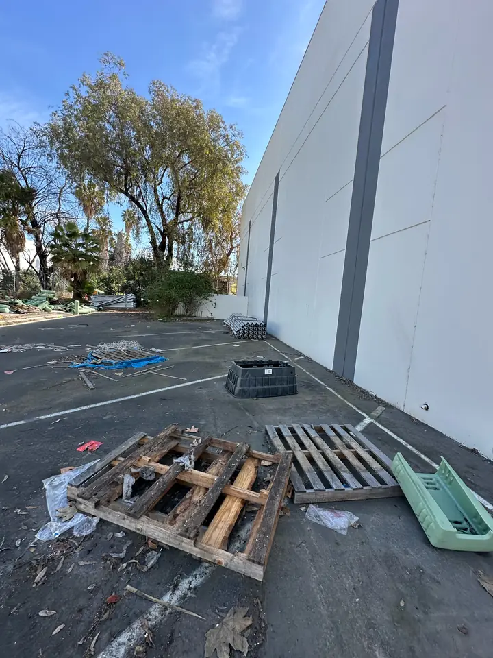 Exterior property work area before pallets and loose debris were removed
