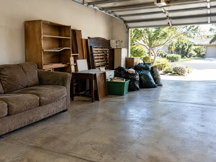 Furniture and bagged contents staged in a garage for large-volume removal